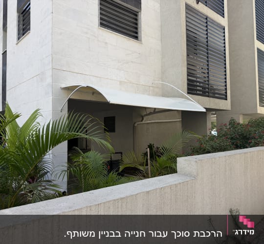 סוכך קבוע קשתי מותקן על קיר חיצוני של בניין מגורים